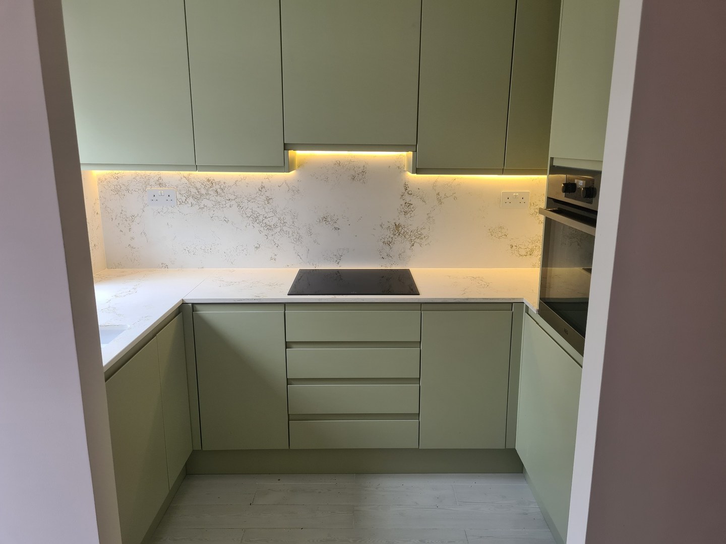 Sage green fitted kitchen with quartz worktops