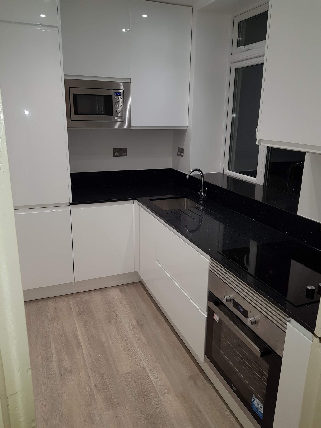 Completed white gloss kitchen with black worktops